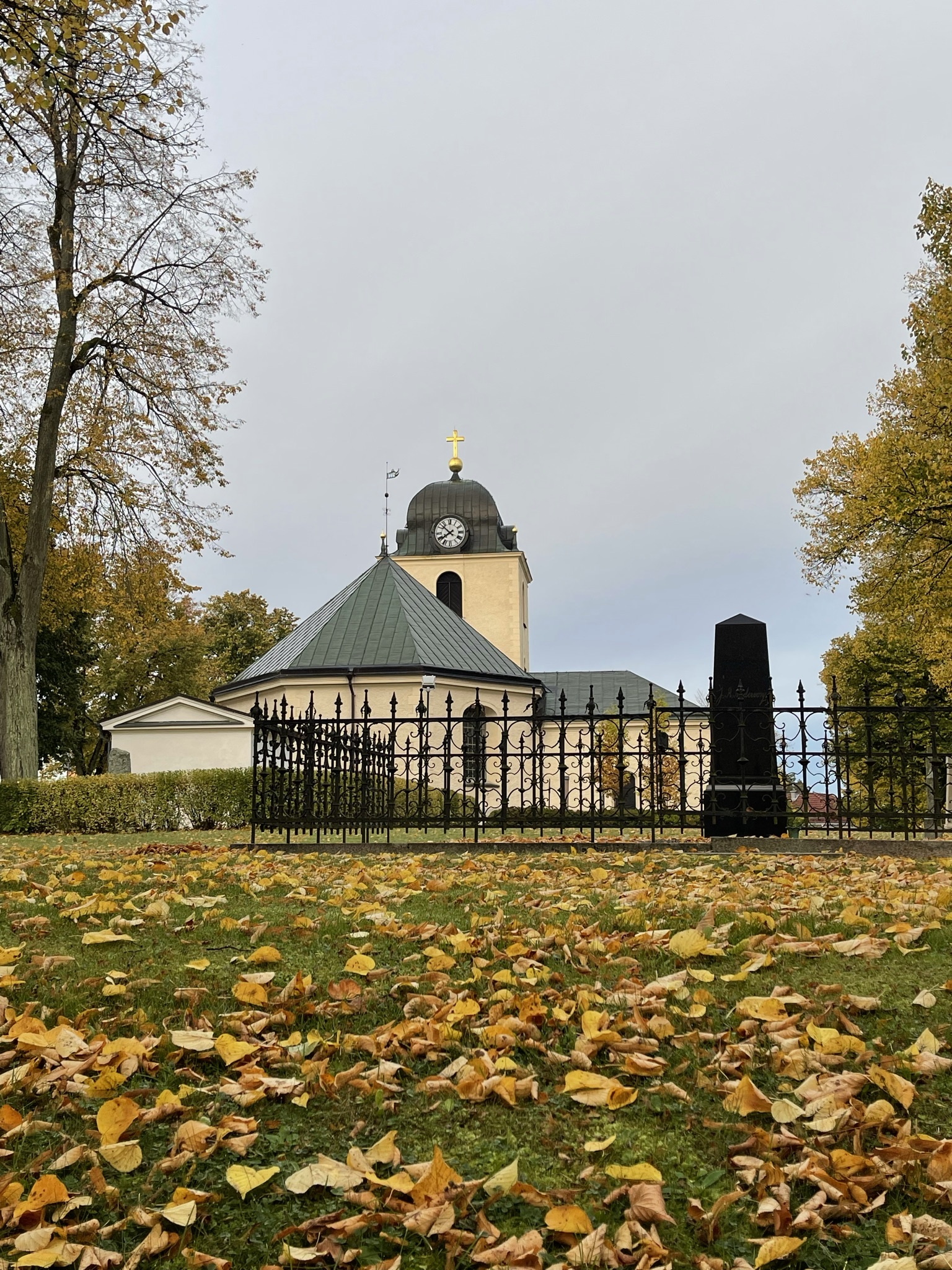 Mjölby kyrka med kyrkogården i förgrunden med höstlöv.