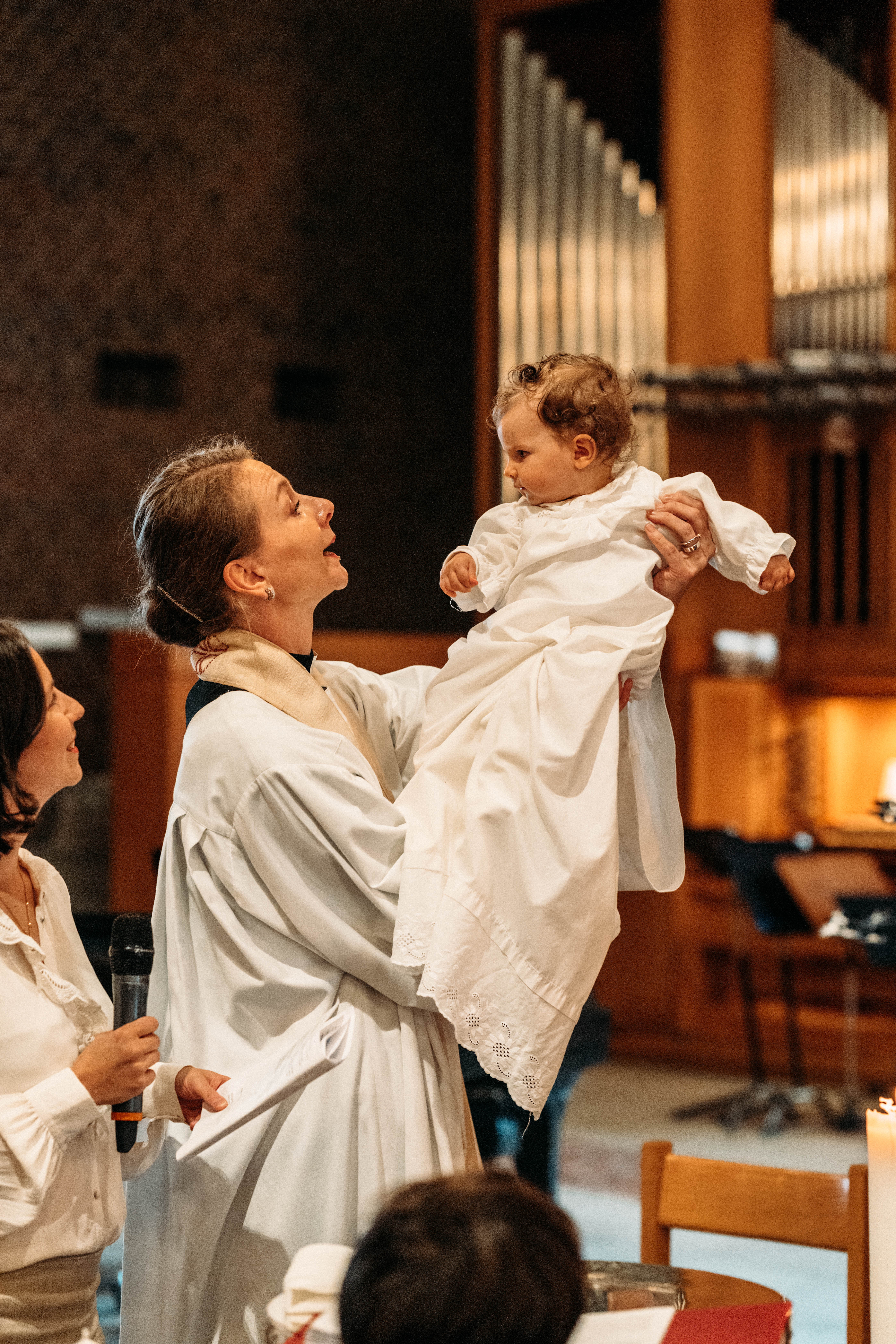 Ett barn döps omgiven av familj i en kyrka.