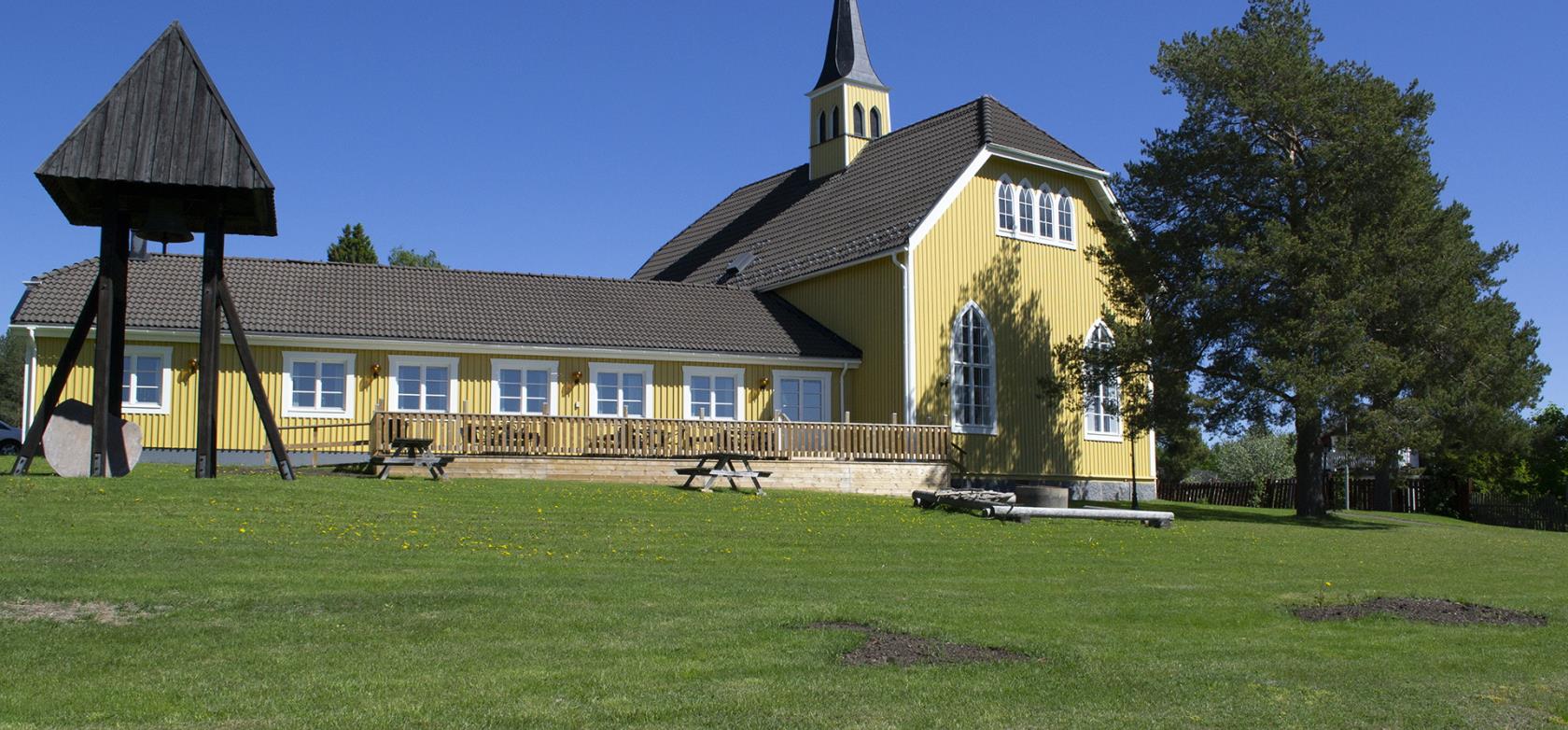 Bilden visar Ersmarks kyrka i Ersmark/Kågedalen. Kyrkan är byggd i trä och gulmålad.  Bilden är tagen på sommarhalvåret. 