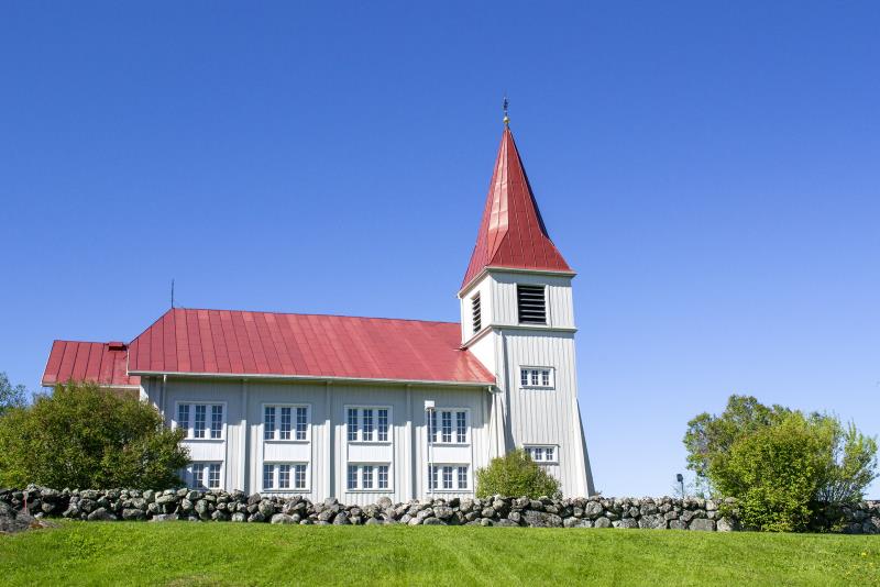 Bilden visar Fällfors stora träkyrka fotograferad i sommarskrud. Kyrkan är vitmålad med rött plåttak. 