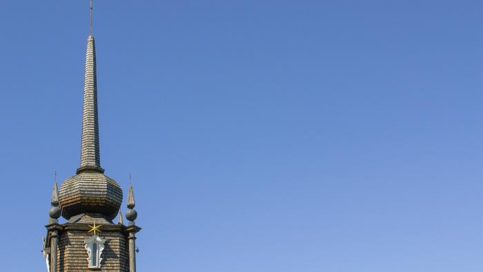 Bilden visar Kåge kyrkas klocktorn. Taket är av trä. Bilden är tagen på sommaren och den blå himlen står som bakgrund. 