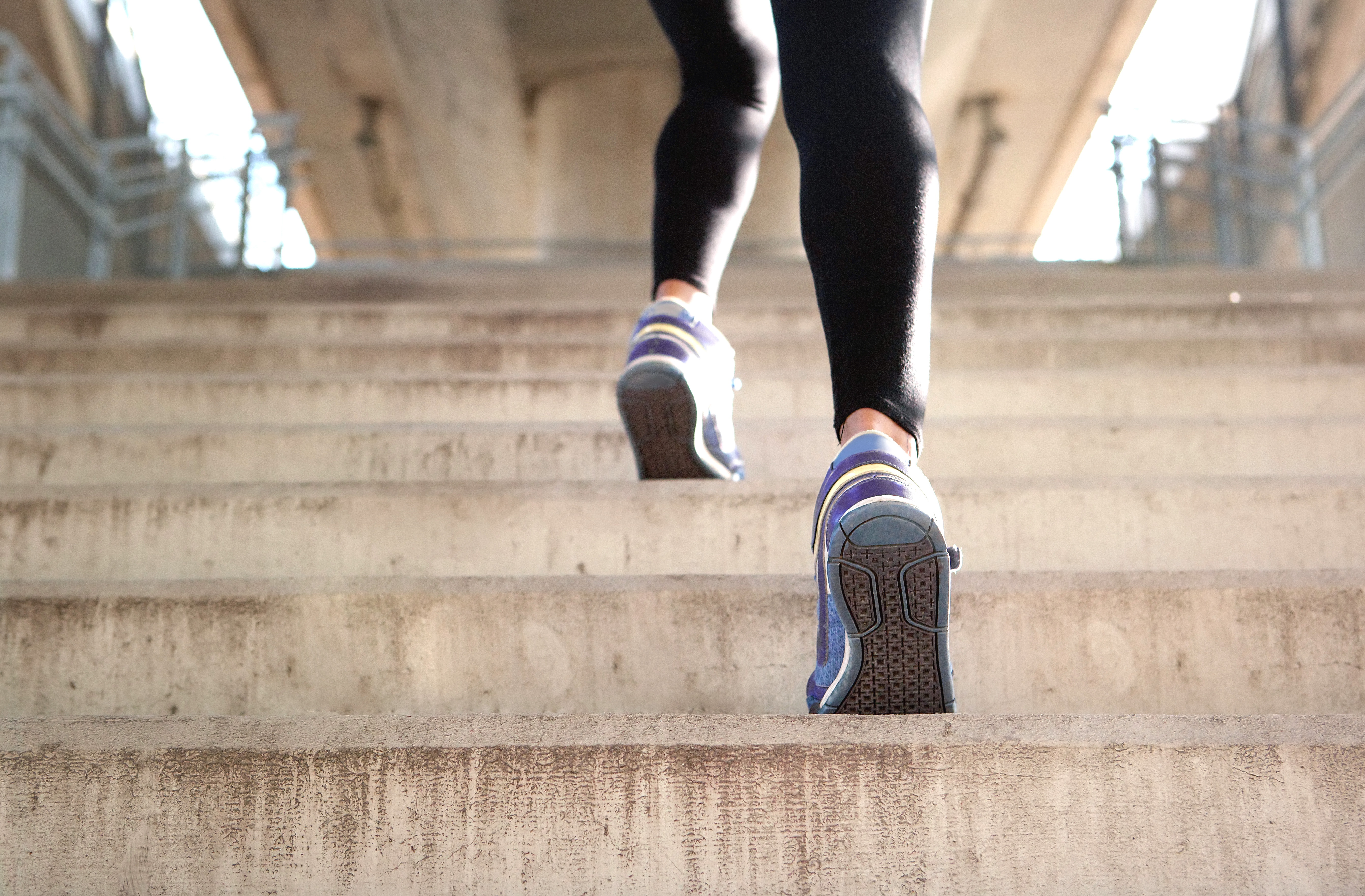 Närbild av två lila skor som är på väg uppför en trappa