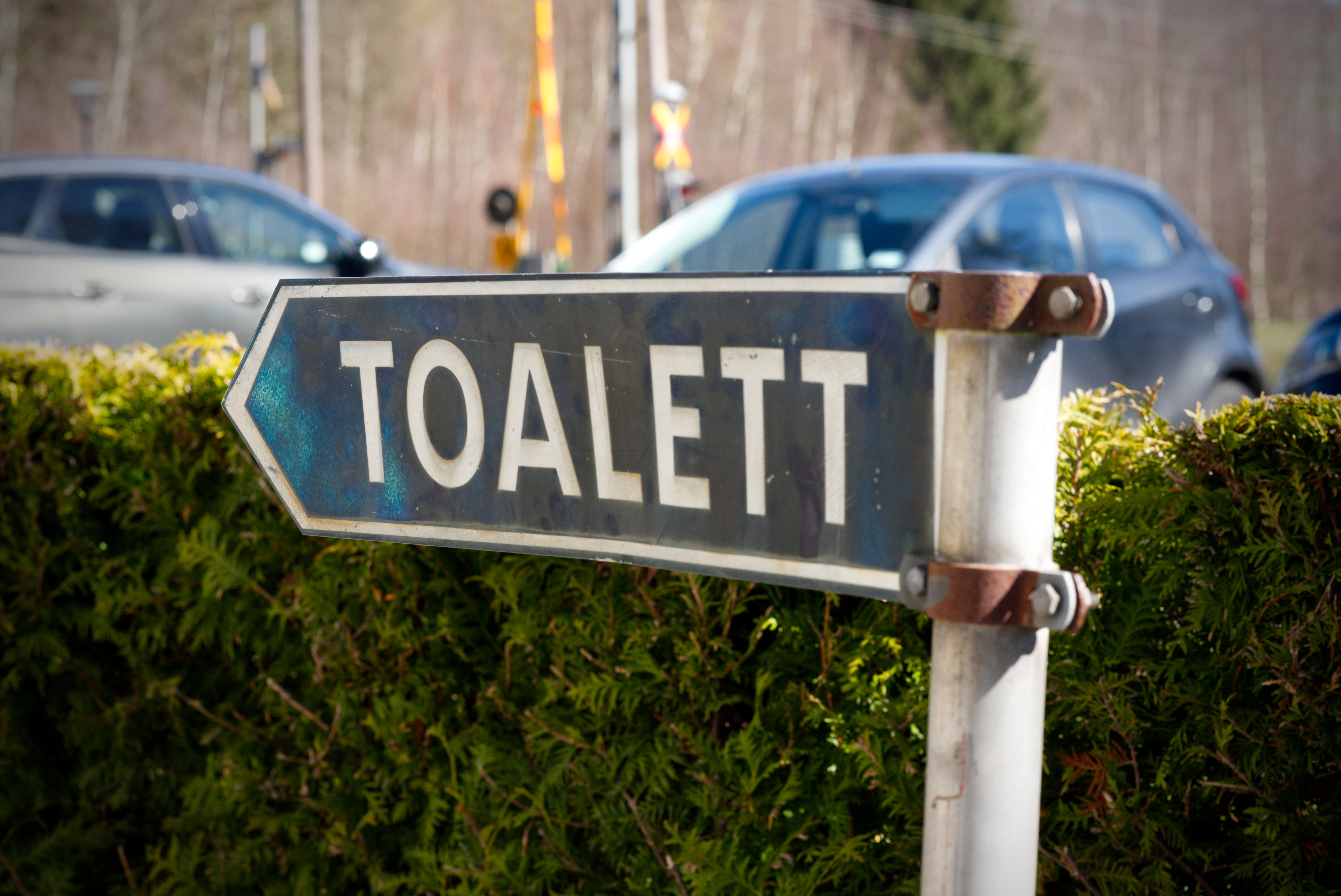 En skylt med texten "Toalett" på, vid parkeringen till en kyrkogård.