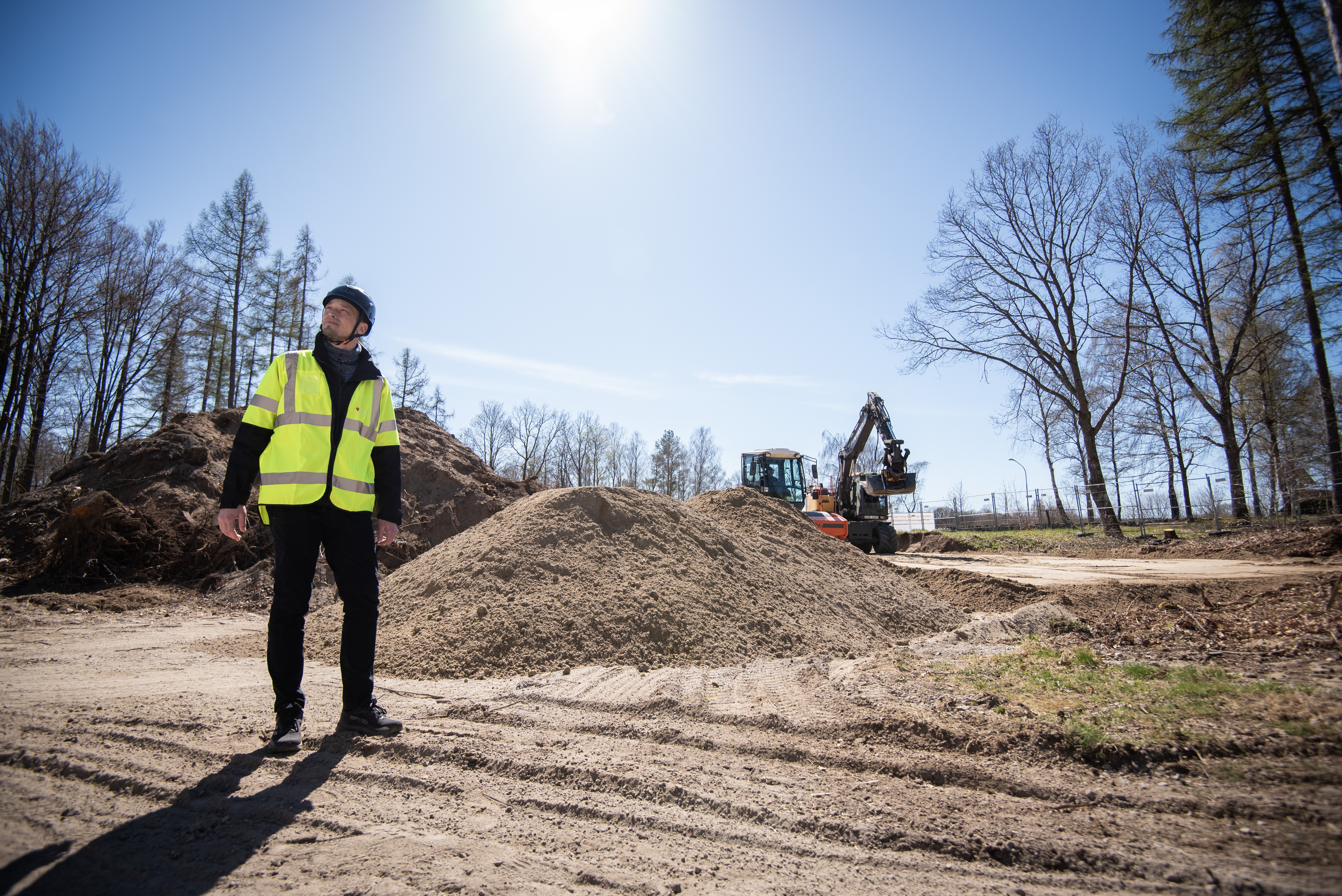En man i skyddshjälm och reflexväst på en byggarbetsplats.