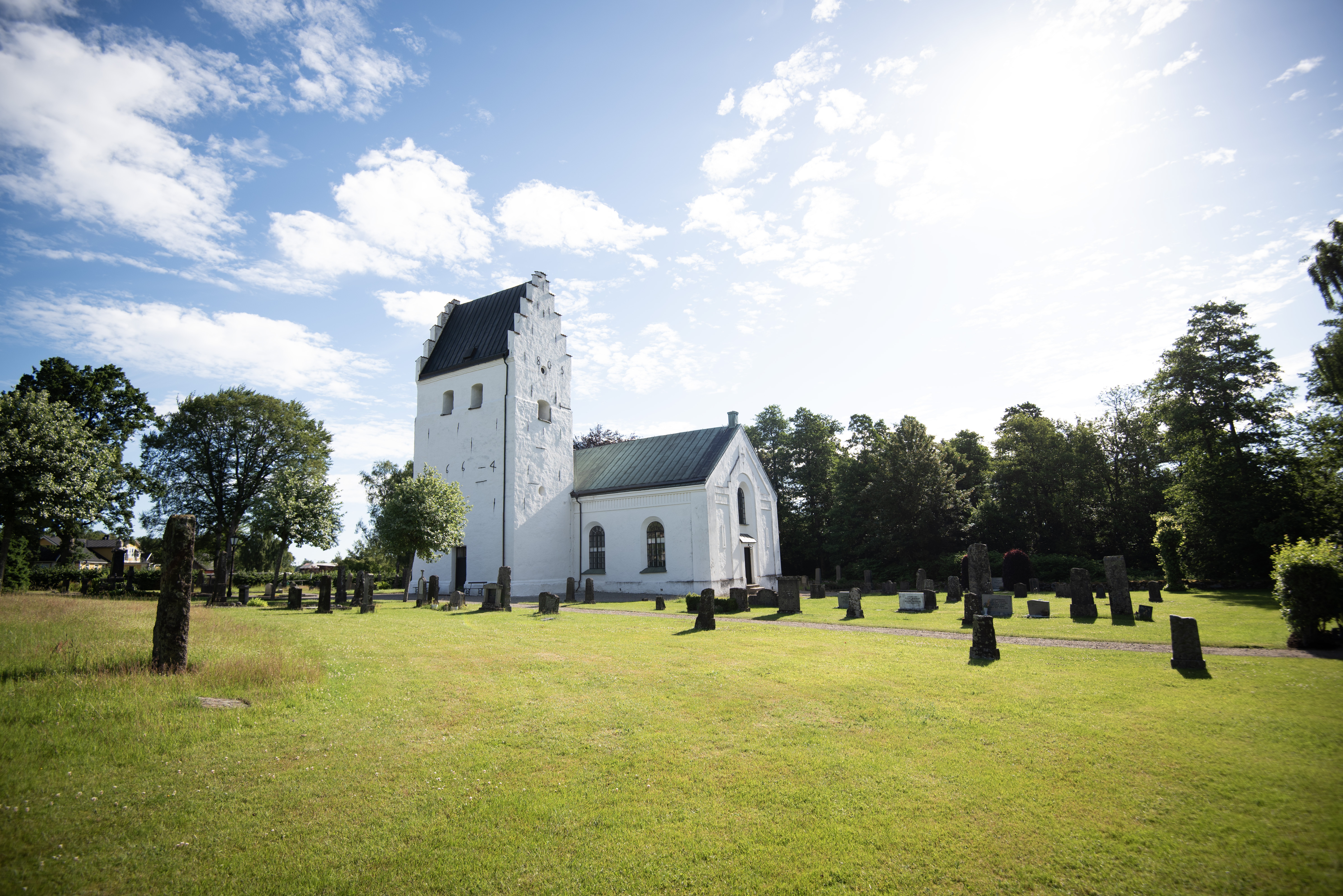 En vit medeltidskyrka en solig sommardag.
