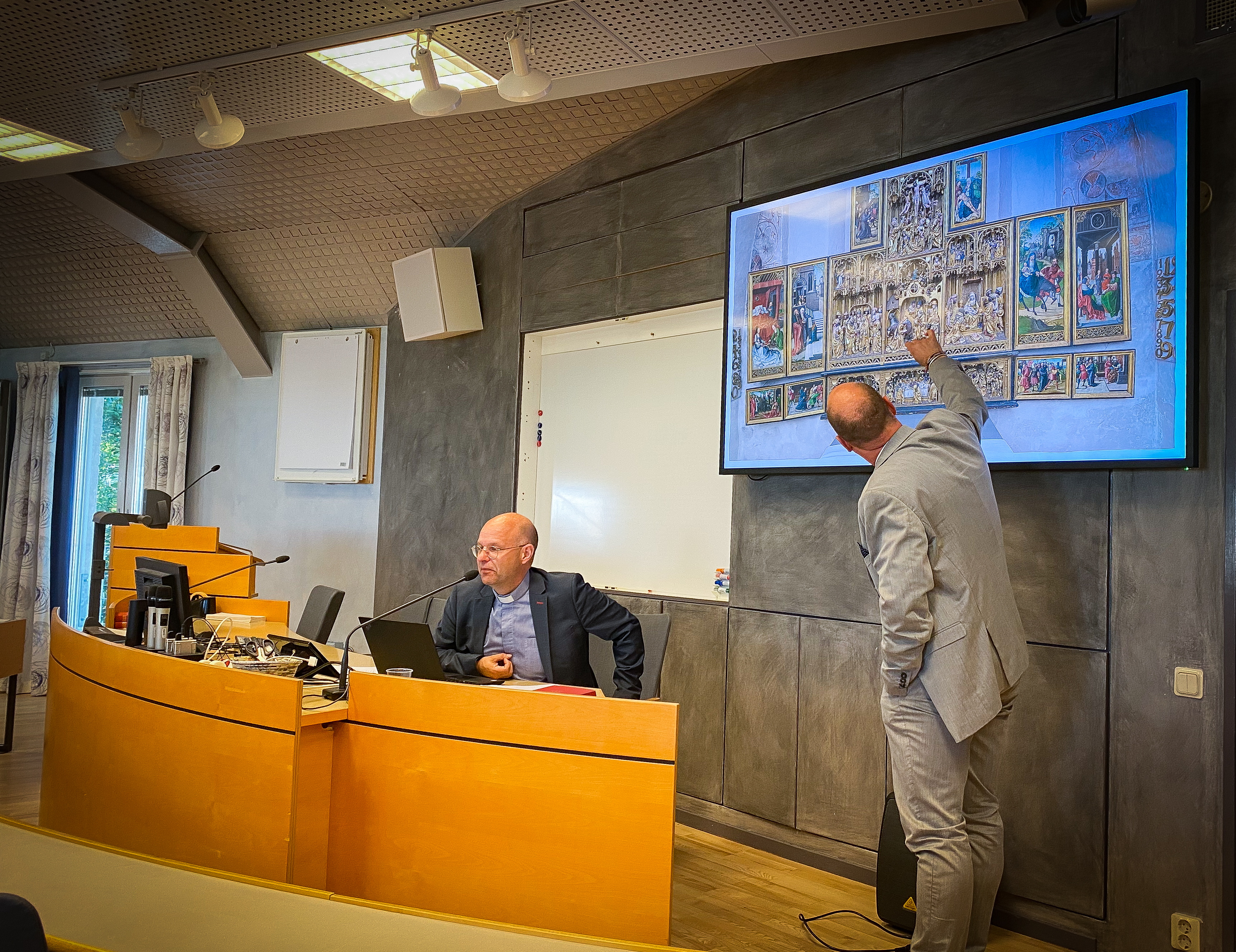 Måns Godée pekar ut detaljer i Skepptunas altarskåp i samband med att appen Storyspot presenterades på Uppsala stift. Stiftsadjunkt Anders Hedman (sittande) är en av projektledarna .