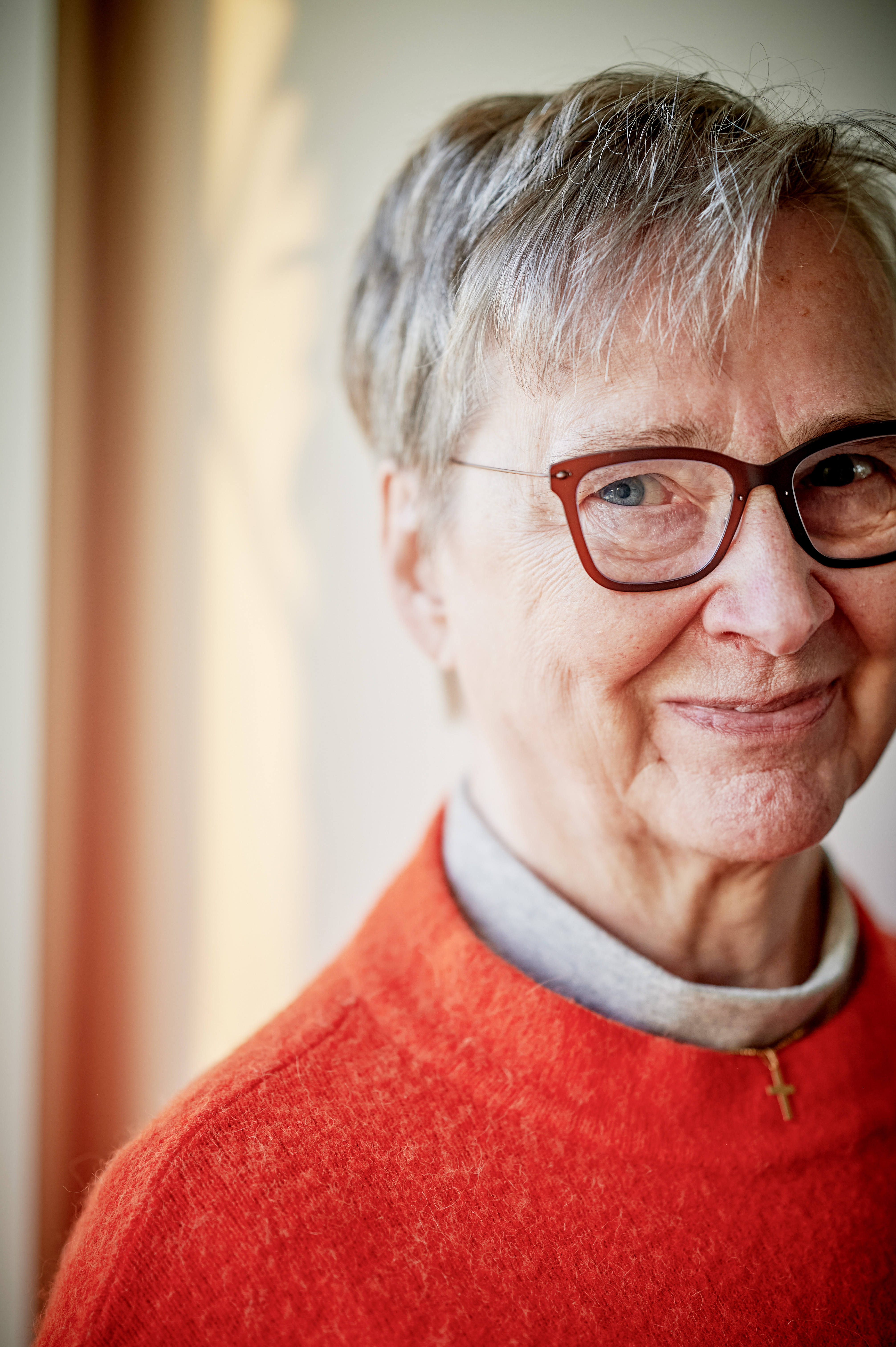 En äldre kvinna med knallorange tröja som pratar.