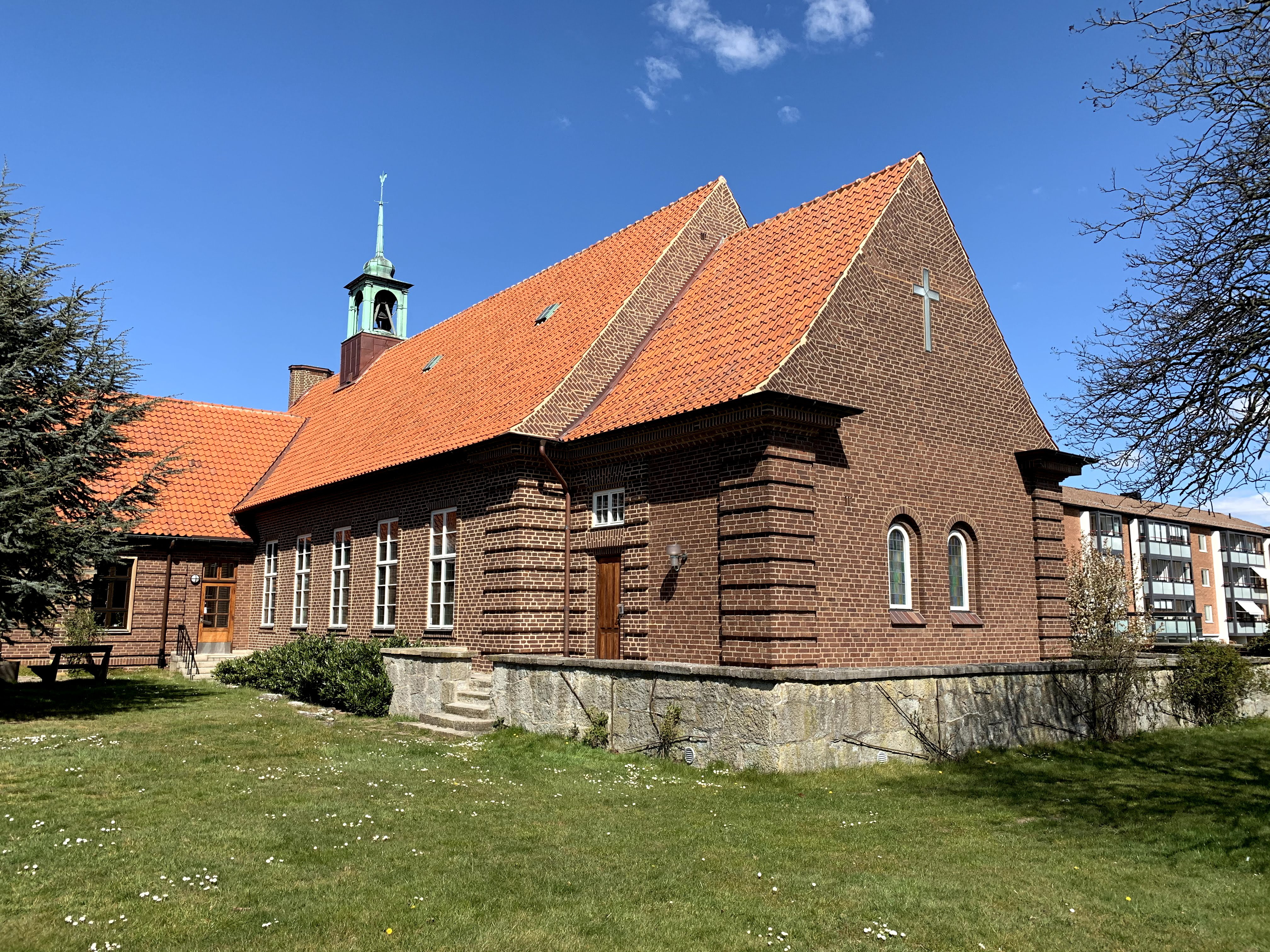 En brun tegelkyrka med gräsmatta framför.