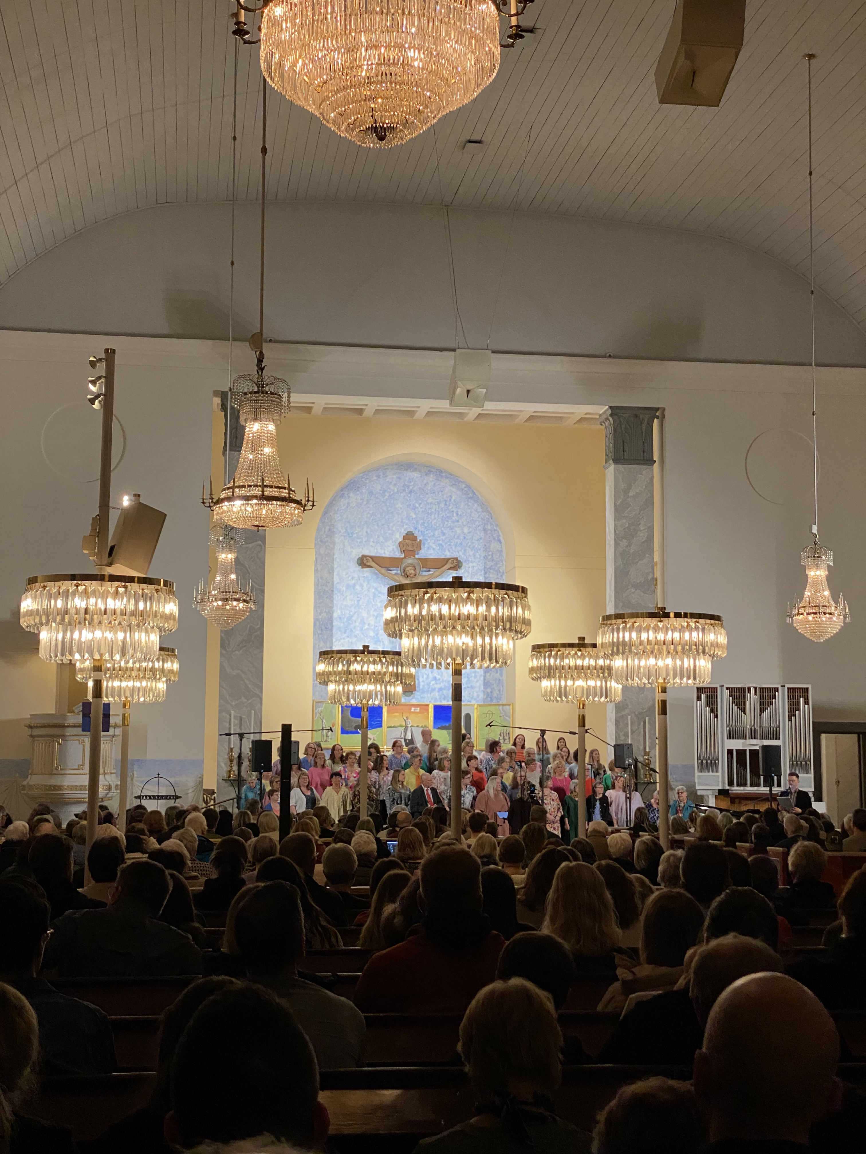 Ett fotografi i Överluleå kyrka. En kör som sjunger och stämningsfullt ljus.