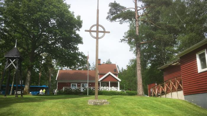 Röda träbyggnader i sommarmiljö. Grön gräsmatta i förgrunden.