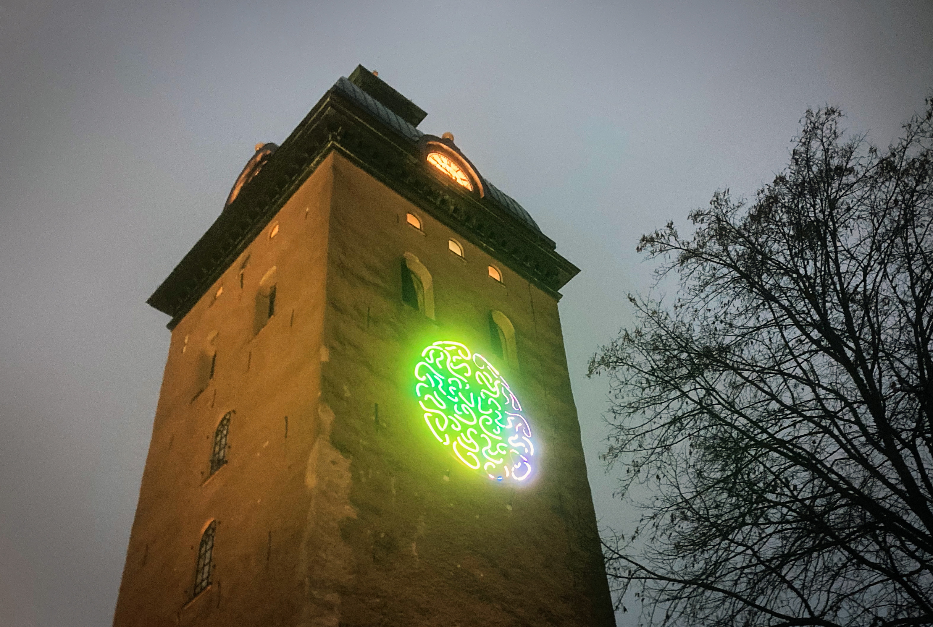 Kyrktorn belyst med ljuskonst föreställande en hjärna.