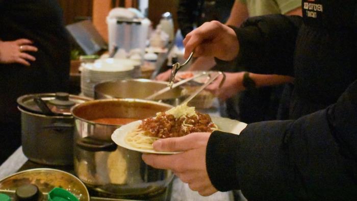 Spaghetti serveras i kyrkolokal. Fokus på maten.