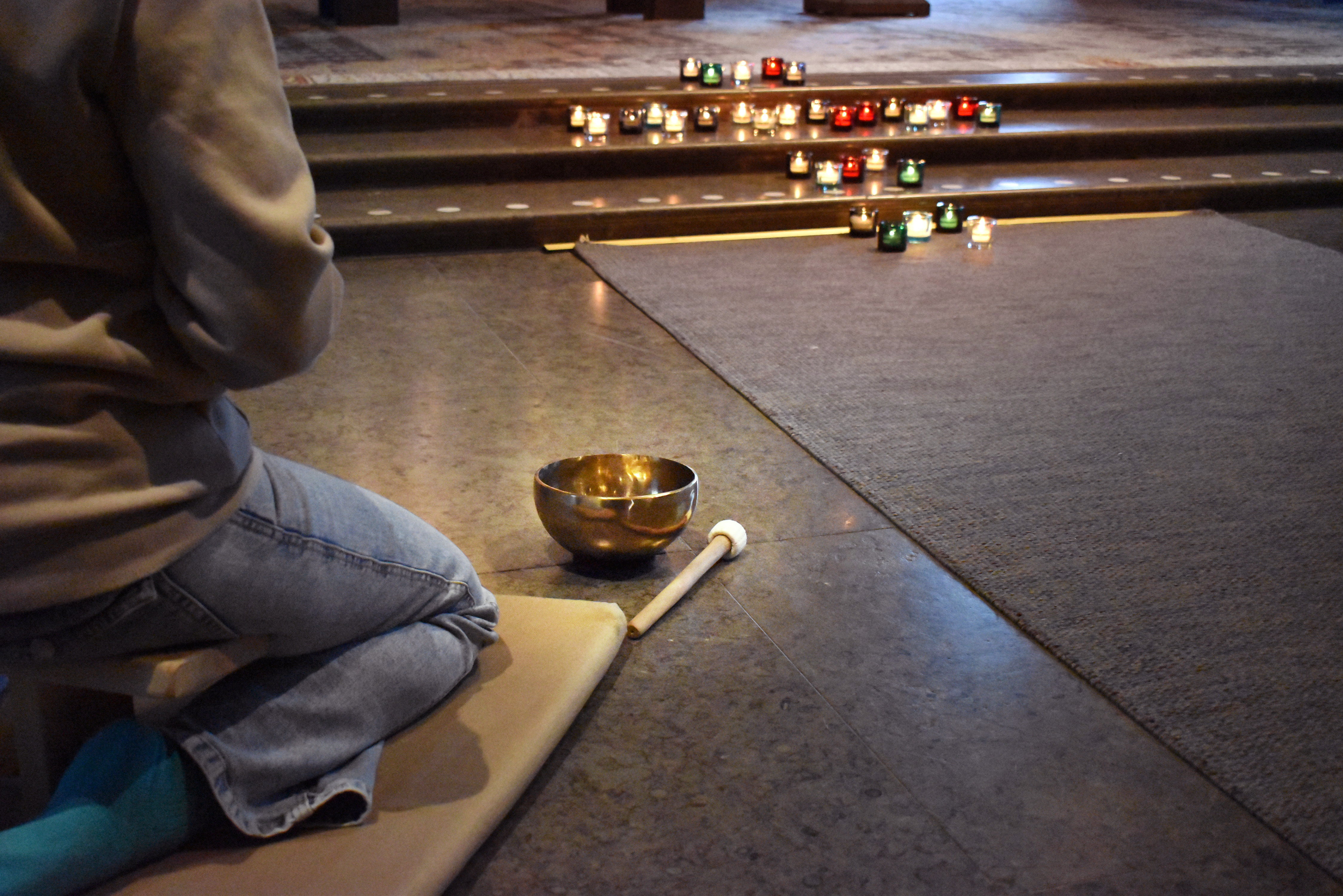 Kvinna sitter och mediterar i kyrka, hennes ansikte syns inte.