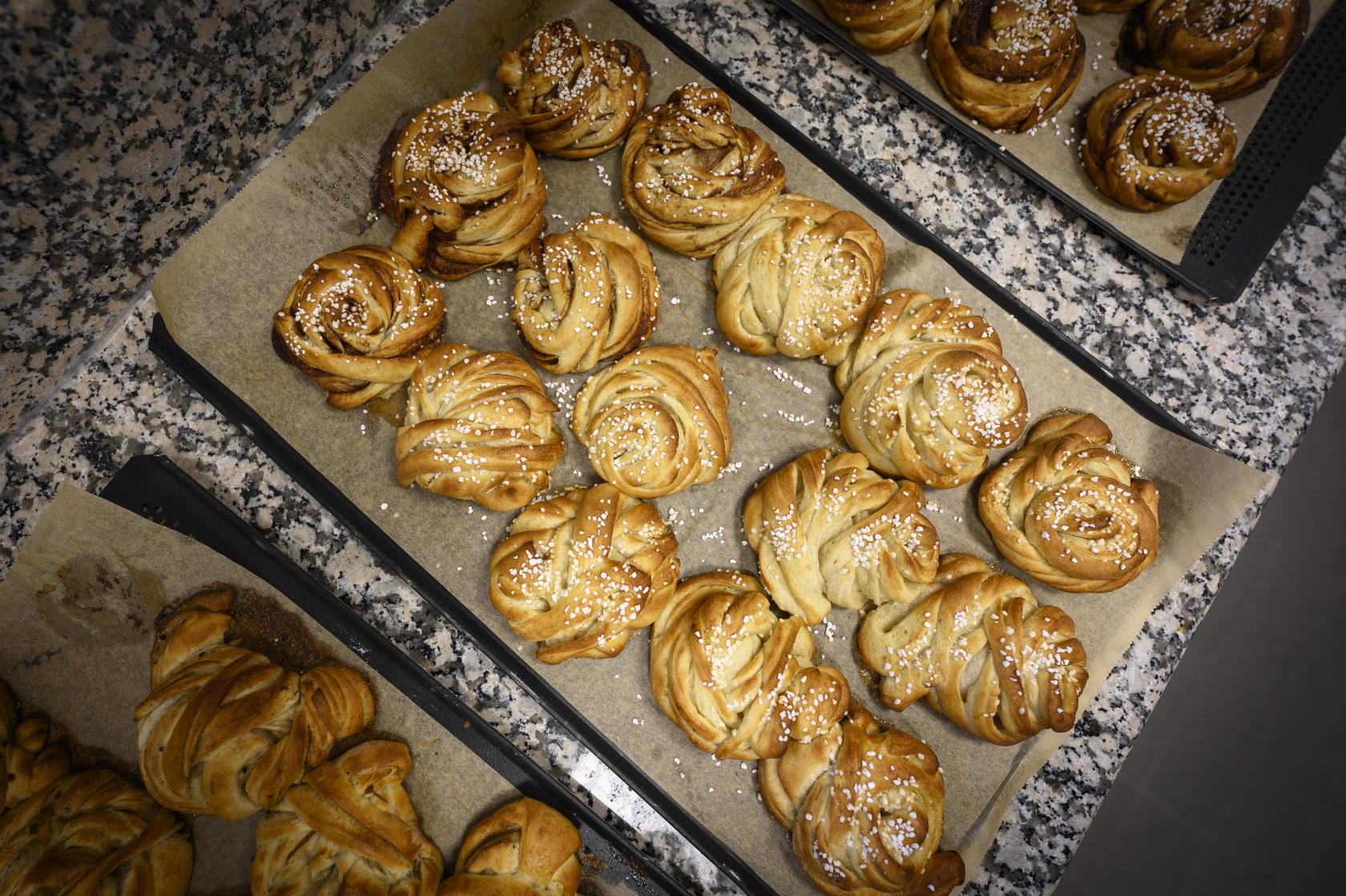 Plåtar med nygräddade kanelbullar.