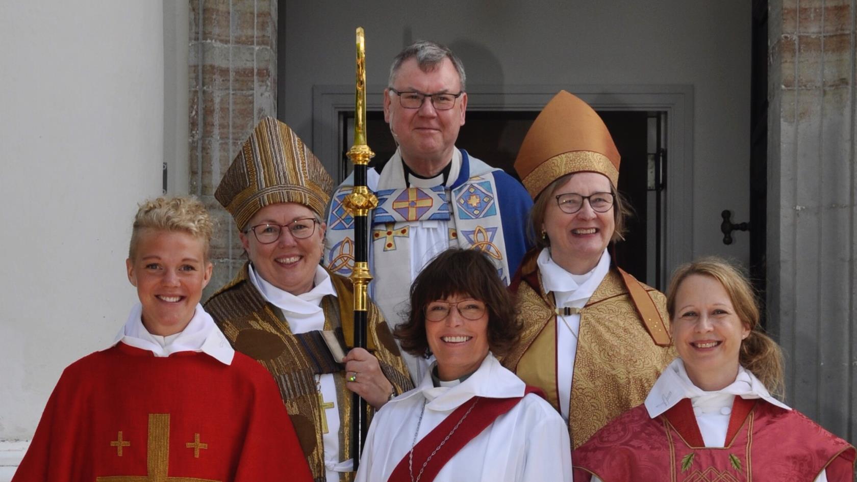 Tre kvinnor som nyligen vigts till präster respektive diakon flankerade av två biskopar och en domprost.