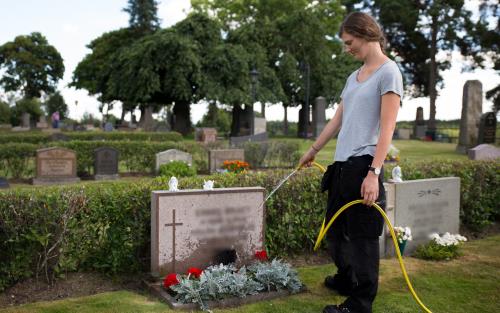 Kyrkogårdspersonal vattnar gravplats.