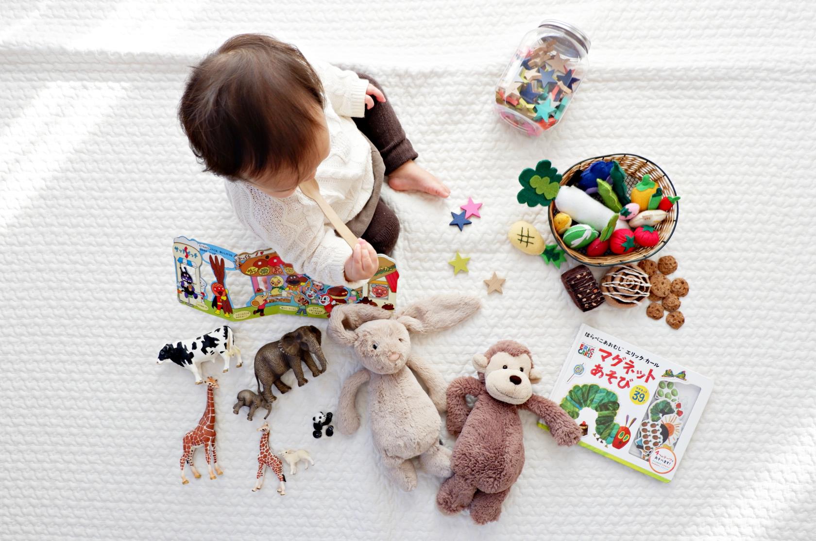 Barn, spädbarn, sitter på matta bland leksaker