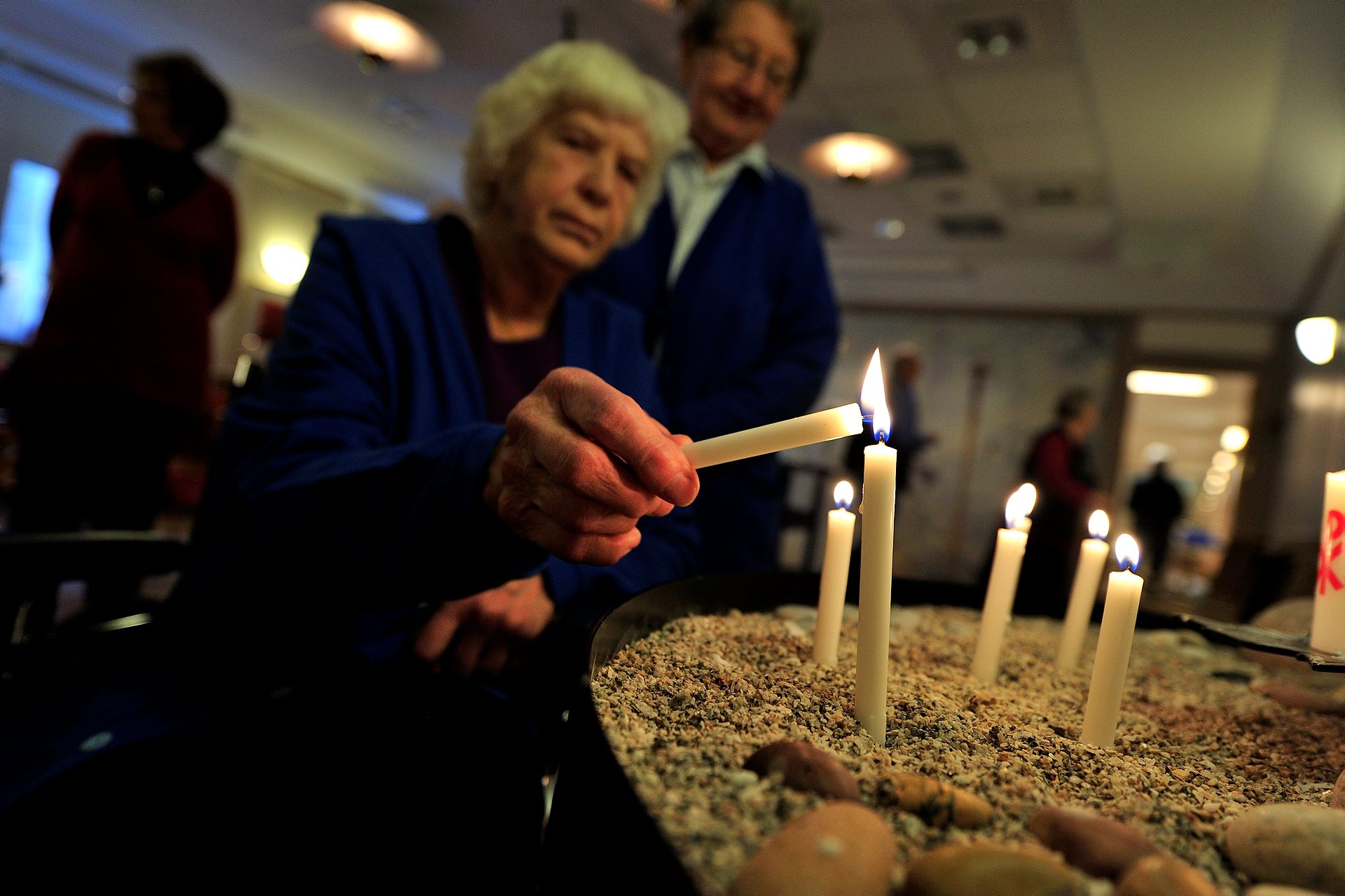 En äldre kvinna tänder ett ljus