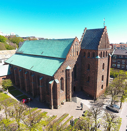 Flygbild på S:ta Maria kyrka i Helsingborg. Kyrkan är byggd på 1400-talet i rödbrunt tegel med grönt tak och trappstegsgavlar.