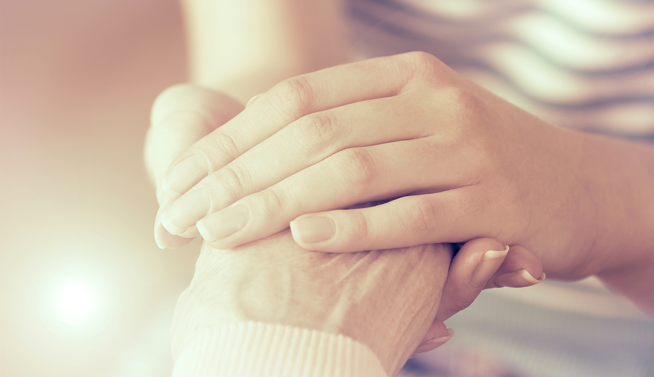 Två händer håller om en tredje hand. 