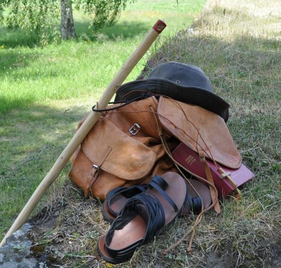 En pilgrim har lagt ifrån sig sin stav, ryggsäck och skor.