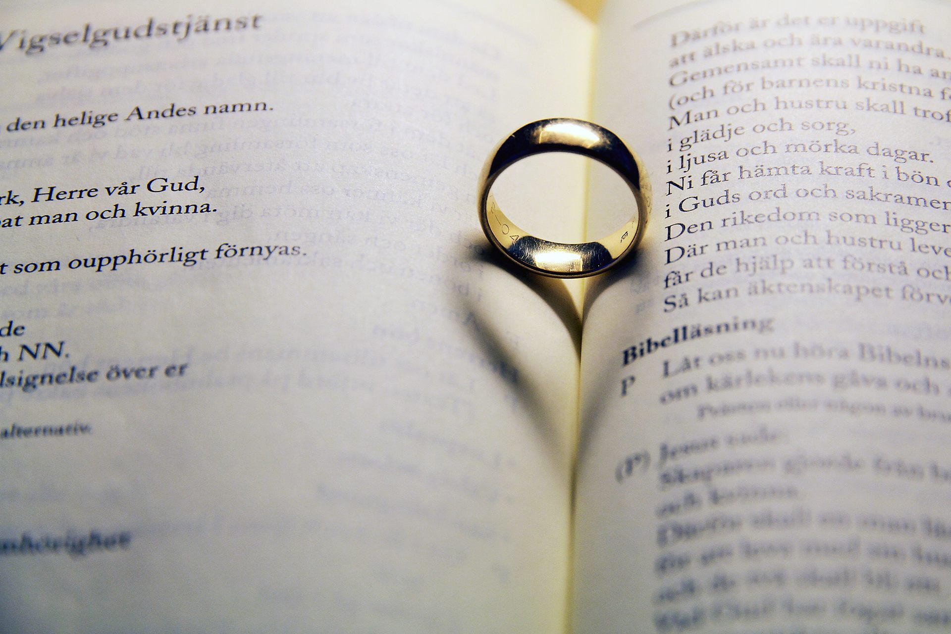En ring ligger i en uppslagen bok. Skuggan av ringen bildar ett hjärta.