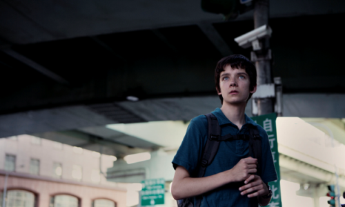 Scen från filmen x+y. Pojke med ryggsäck tittar på något.