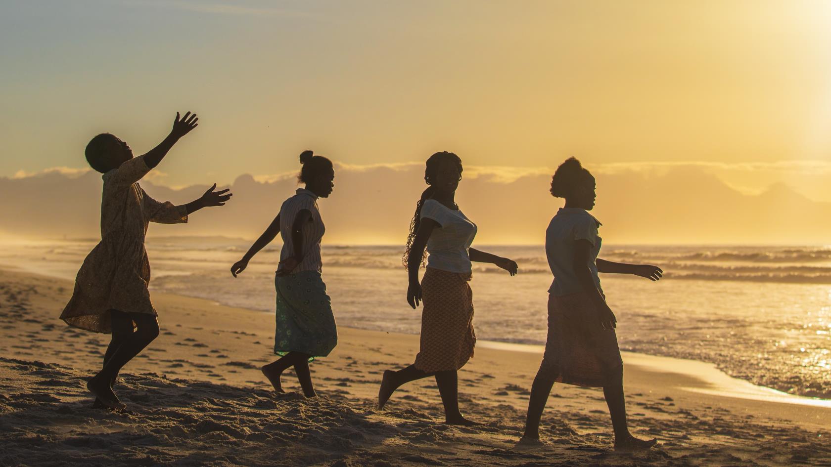 Fyra kvinnor på en strand i solnedgång.
